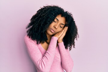 African american woman with afro hair wearing casual pink shirt sleeping tired dreaming and posing with hands together while smiling with closed eyes.