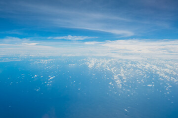 Aerial view scene of an big ocean or sea in the big ocen with white fluffy clouds and bright blue sky background.
