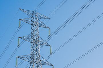 High voltage pole stand agianst white clouds and clear blue sky background with copy space