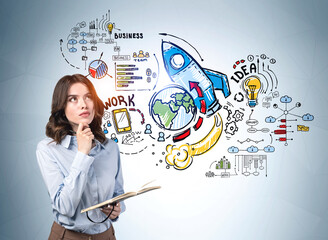 Businesswoman in blue shirt near sketch with icon of rocket