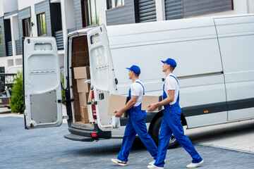 Two removal company workers are loading boxes and furniture into a minibus.