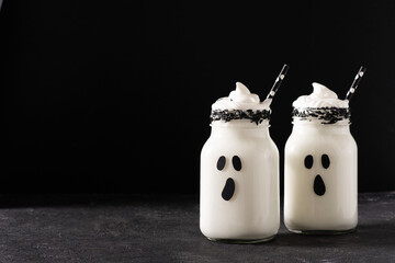 Funny white milkshake ghost cocktail on black background, halloween concept