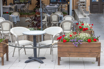 Beautiful landscape view of outdoor cafe. White chairs and tables  under umbrellas with flower boxes. Sweden