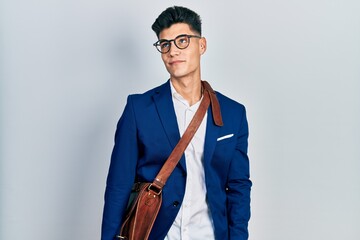 Young hispanic man wearing business clothes smiling looking to the side and staring away thinking.