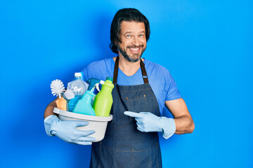 Middle age caucasian man holding cleaning products smiling happy pointing with hand and finger