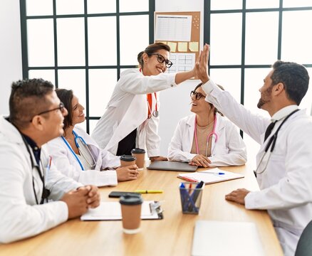 Group of doctor smiling happy and looking parters high five at clinic office.