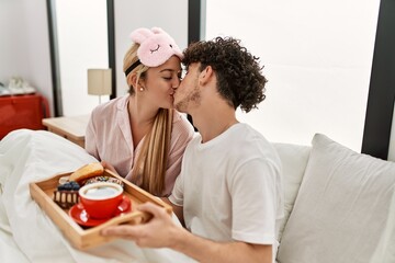 Young beautiful couple having breakfast on the bed at home.
