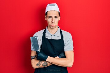 Young hispanic man wearing professional apron holding knife skeptic and nervous, frowning upset because of problem. negative person.