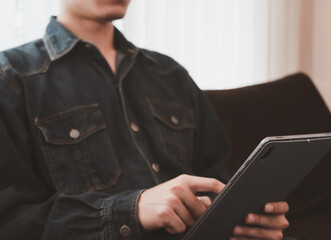 Businessman using tablet searching information, shopping online, play internet social media in the living room