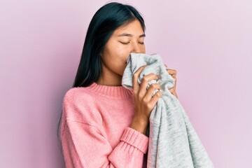 Young asian woman smelling laundry scent from clean sweater