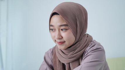 beautiful woman in hijab smiling sitting on the sofa