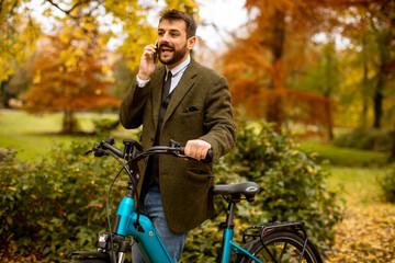 Fototapeta na wymiar Young man with electric bicycle in the autumn park