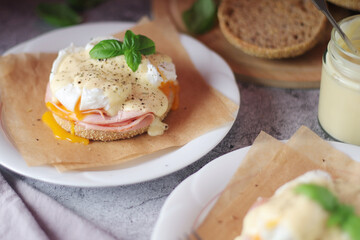 Egg benedict sandwiches - muffin with poached egg, ham and hollandaise sauce