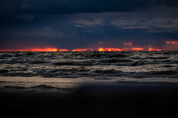 Fantastic view of the dark overcast sky. Dramatic and picturesque evening sunset scene over the sea. Storm clouds, storm passing over sea, dramatic clouds after storm at sunset. Defocused