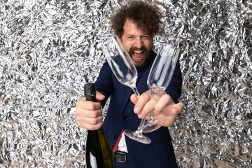 laughing young businessman holding glasses and champagne bottle