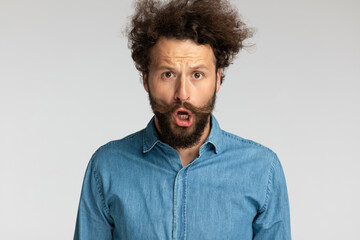 shocked young man in denim shirt opening mouth and making an astounded face