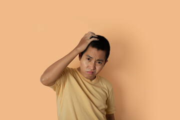 Portrait of young man wearing t-shirt feeling disappointed on orange background.