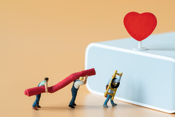 Miniature people Labor Worker walking carry ladder and red carpet for decorate stage with red heart using as special event making service business or Valentine day 14 February Lovely Happy Family idea