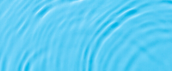 Wave from a drop of water on blue water under natural light. Top view, flat lay. 