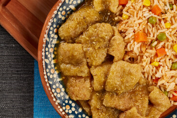 Chicharrón en salsa verde con arroz rojo mexicano servido en plato de barro