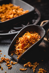 Homemade fried onions in iron kitchen scoop with black pan on black