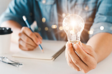 Innovation through ideas and inspiration ideas. Human hand holding light bulb to illuminate, idea...
