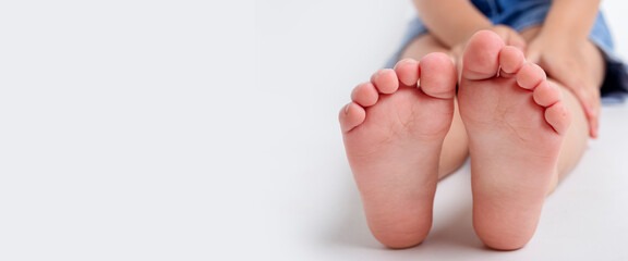 Bare feet of a child in the studio on a light background. Banner