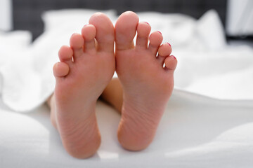 Girl feet in a white bed in the morning. Enjoy and relax in the morning. Smooth skin on the heels.