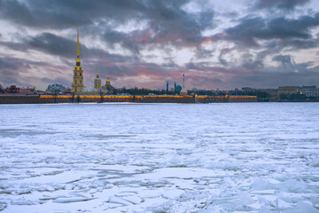Fototapeta premium Saint-Petersburg in winter. Ice on the Neva River on the background of the Peter and Paul Fortress. Petersburg rivers. Russian cities in winter. Peter and Paul Fortress and cracked ice on Neva River.