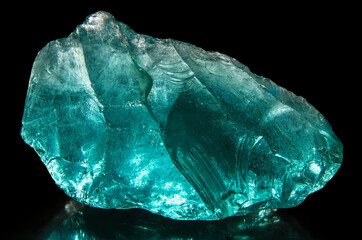 Fototapeta premium Turquoise piece of glass on a black background.