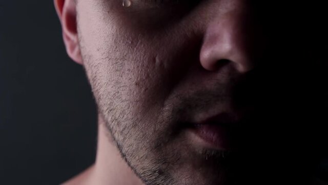 Despair depressed man crying, tear flowing down his cheek, close-up. Pain and suffering concept