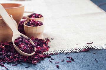 Dry hibiscus tea in wooden spoon and small cups