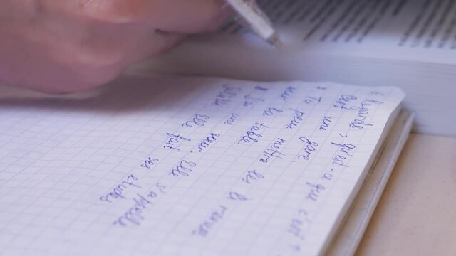 female hand making notes in notebook while studying french write text