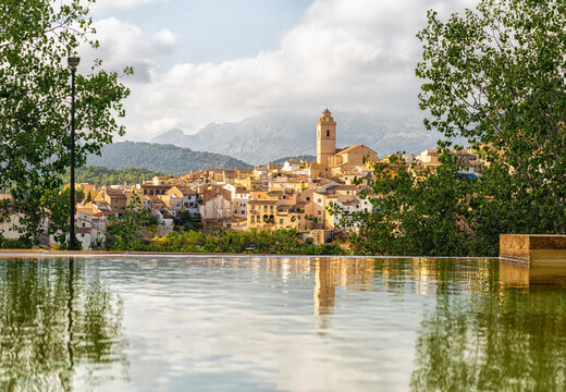Views of the town of Polop (Alicante, Spain), with its reflection in the water, on a sunny afternoon and cloudy skies.