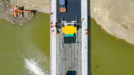 Aerial view on people with mechanization laying, spreading asphalt