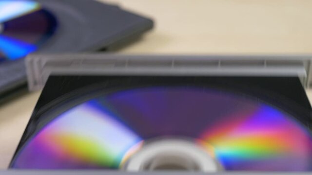 hand takes out cd disk with a box and insert it to dvd player