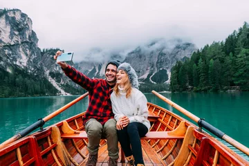 Foto op Plexiglas Romantic couple of adults in love taking selfie on a boat visiting an alpine lake at Braies, Italy - Couple, technology, travel and happy lifestyle concept - Cold colours. © Davide Angelini