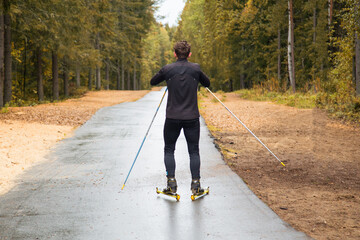 A man on a roller ski rides in the park.Cross country skilling.