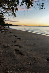 photo of footprints on the beach sand, in the morning