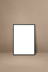 Black picture frame leaning on a beige wall