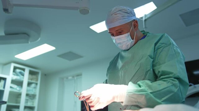 Liposuction Procedure To A Patient With Surgical Tools. Professional Doctor In Mask Performing An Operation Using Medical Tools In Clinic.