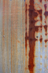rusty gray metal surface with orange and brown tones in abstract shapes  - worn vertical background with  scratches and grooves  for a wallpaper	