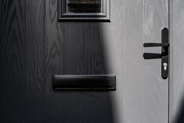 Abstract view of a modern, thermoplastic door partially seen in heavy shadow.