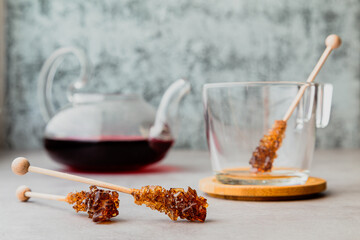 a sugar lollipop lies next to a mug and a teapot with karkade