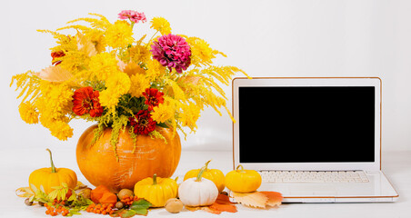 Autumn concept with notebook and festive decoration of flowers in pumpkin for Thanksgiving day.