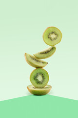 Fresh green kiwi fruit food balance on green geometric paper background, vegetarian and vegan diet...