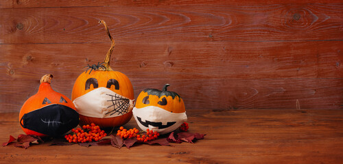 A new normal concept. A pumpkin for Halloween in a medical mask on a brown background. Copy space.