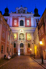 the facade of a baroque church decorated with columns and statues in the evening