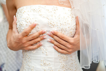 the bride holds the bodice of the wedding dress