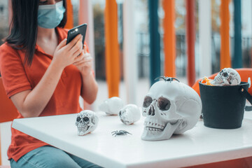 Niña joven con mascarilla haciendo una foto a las calaveras de celebracion de Halloween para...